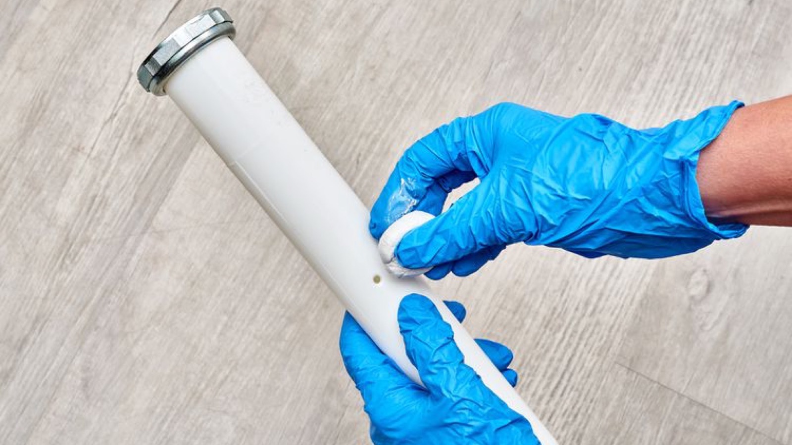 Gloved hands repairing a residential PVC pipe fitting